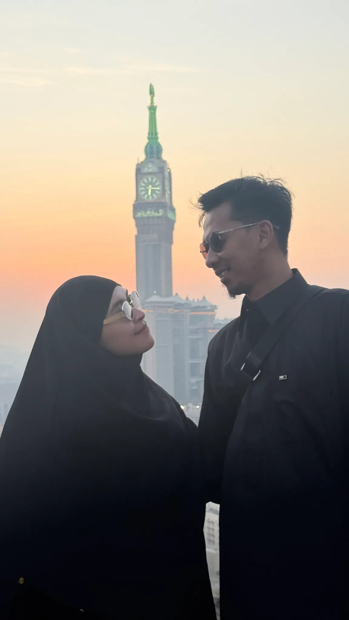 Pasangan jamaah dengan latar menara jam Makkah